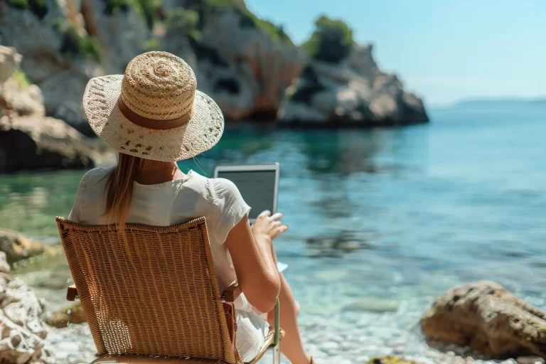 Žena na pláži pracující na notebooku – připojení díky Starlink internetu na cestách.