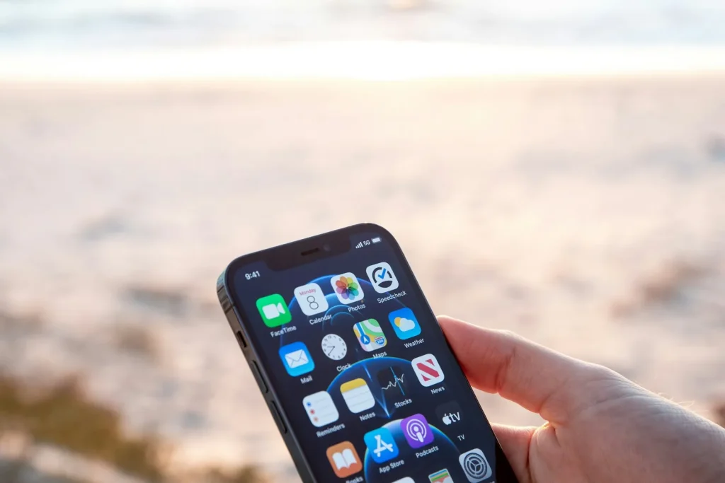 Muž drží chytrý telefon s měřením rychlosti internetu na pláži u moře při západu slunce