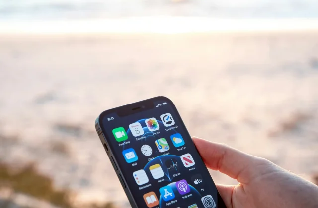 Muž drží chytrý telefon s měřením rychlosti internetu na pláži u moře při západu slunce